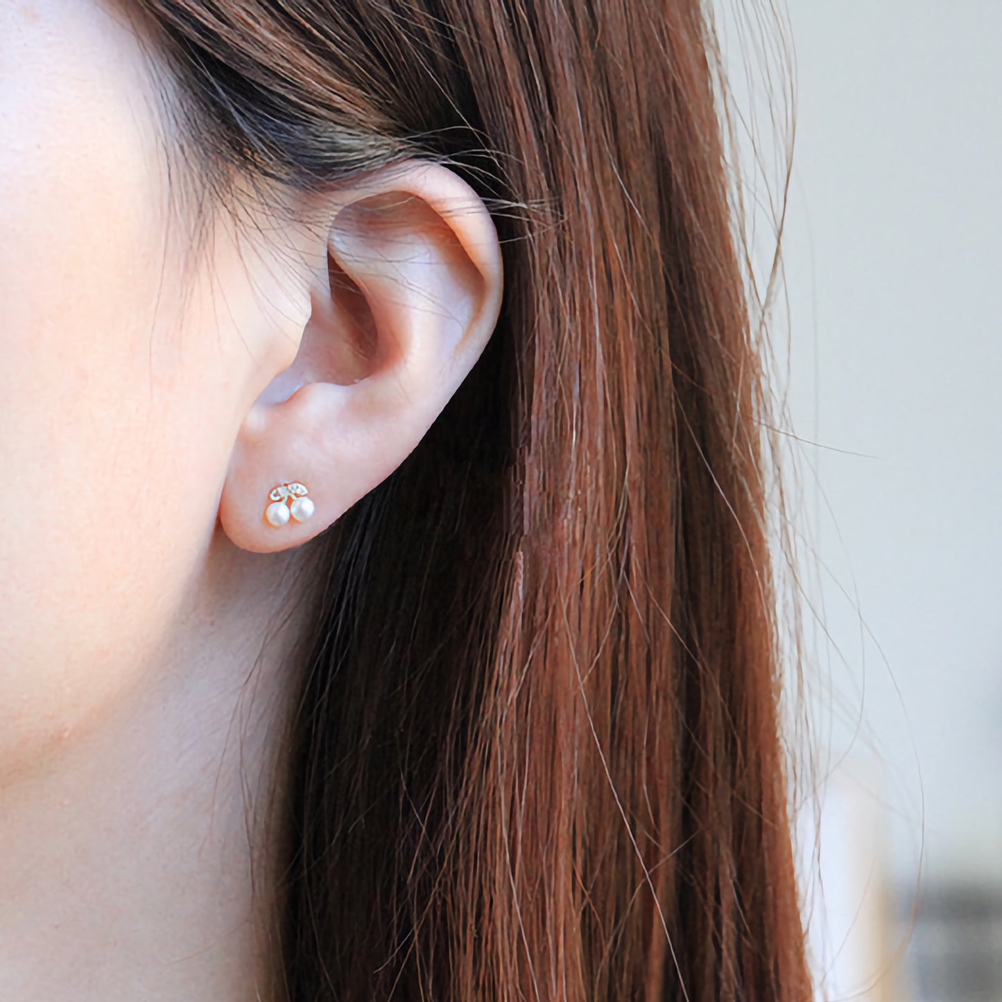 A model wearing the solid gold pearl cherry studs