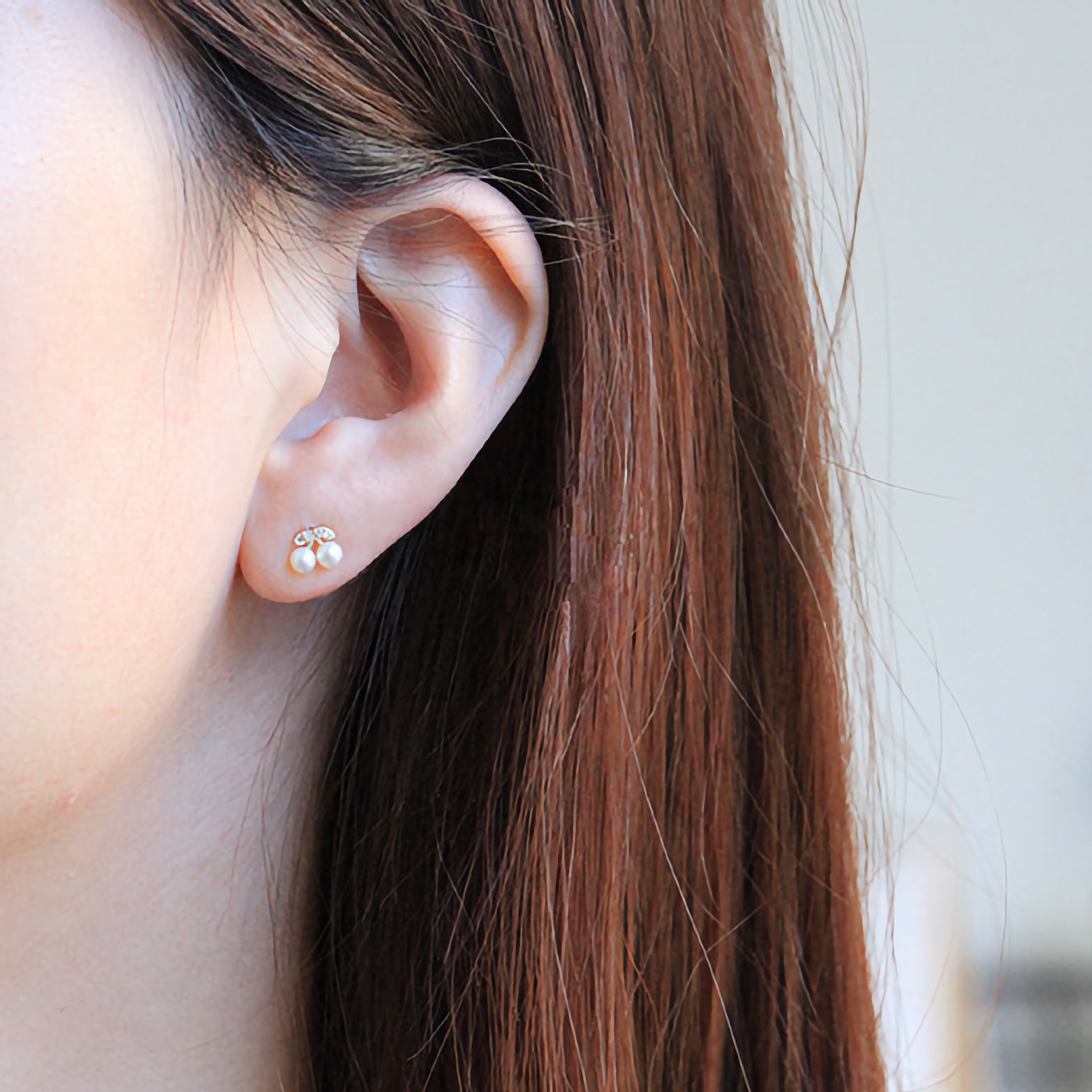 A model wearing the solid gold pearl cherry studs